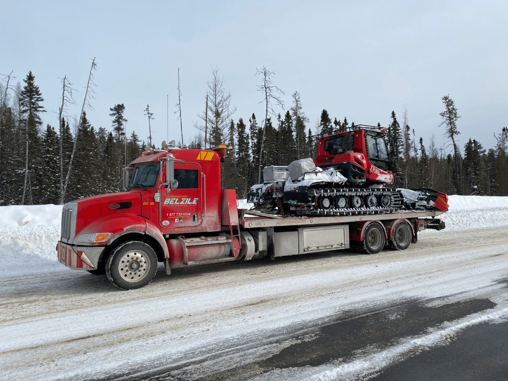 Remorqueuse Belzile transportant une dameuse sur neige.